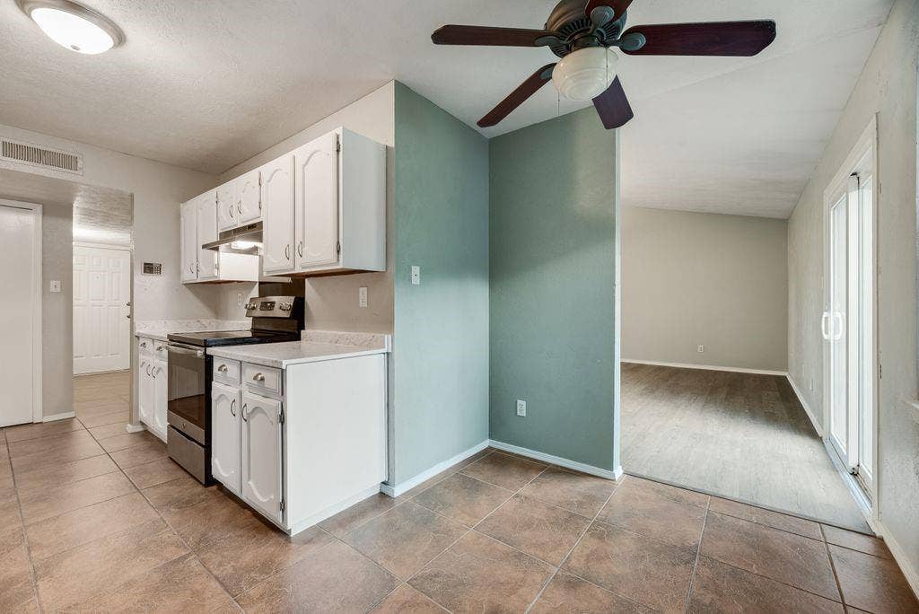 316 Matterhorn Street, Cedar Hill, TX 75104 Kitchen featuring white cabinetry, dark countertop surfaces, stainless steel appliances, and brown tile flooring