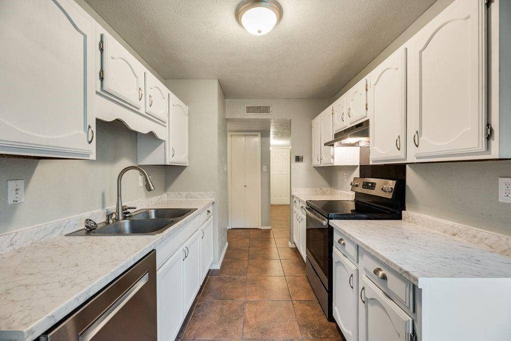 316 Matterhorn Street, Cedar Hill, TX 75104 Galley kitchen featuring white cabinetry, light-colored countertops, a stainless steel double sink with a gooseneck faucet, a built-in dishwasher, and a black electric range with an overhead vent hood