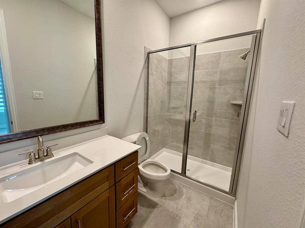 2930 Eleanor Drive, Prosper, TX 75078 Bathroom featuring a textured wall, vanity, and a shower stall