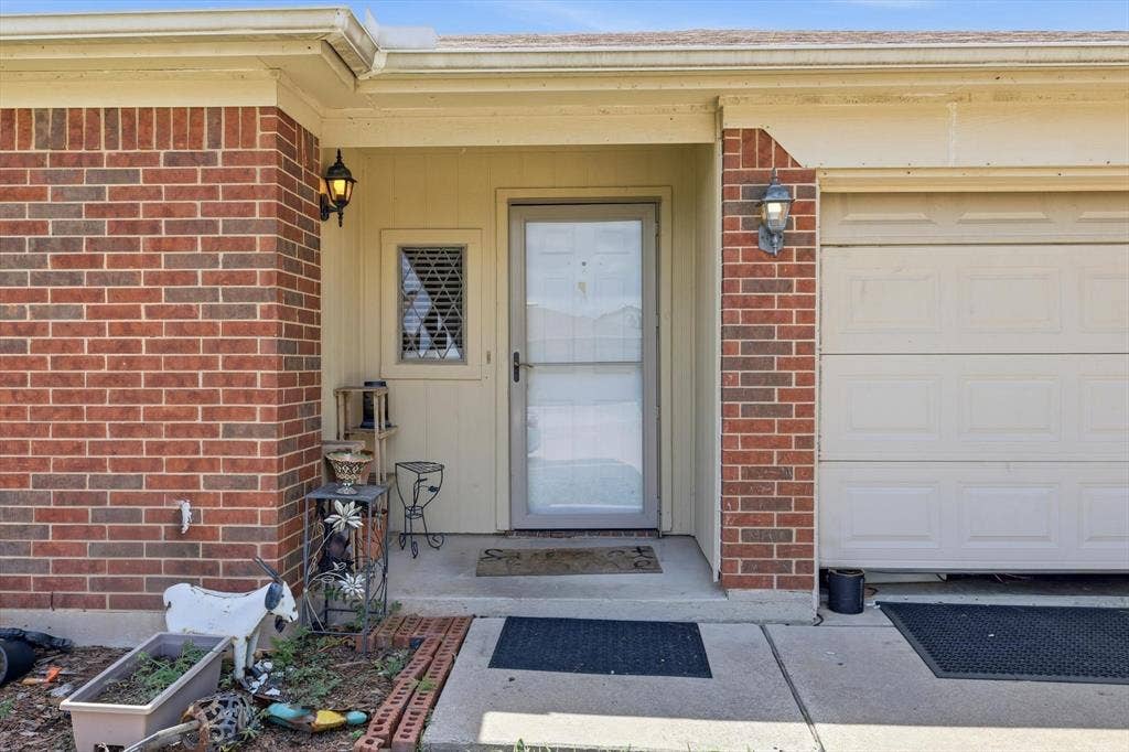 6406 Nicole Way, Arlington, TX 76002 Brick facade entry with a glass storm door, decorative window panel, and exterior lighting fixtures