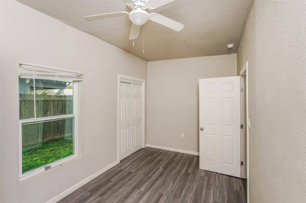 2402 Summer Avenue, Waco, TX 76708 Room featuring wood-finish flooring, a ceiling fan with light fixture, a window providing natural illumination, bi-fold closet doors, and a six-panel door