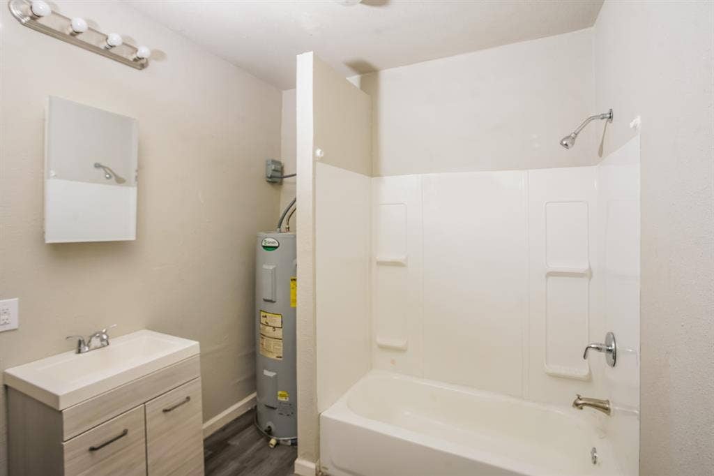 2402 Summer Avenue, Waco, TX 76708 Bathroom featuring a bathtub with shower, single vanity, and wood-finish flooring