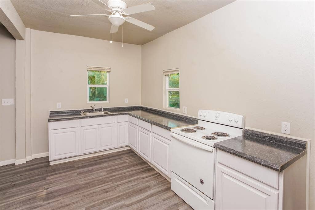 2402 Summer Avenue, Waco, TX 76708 Kitchen area featuring wood-finish flooring, white cabinetry, dark countertops, a double basin sink, and a white electric range
