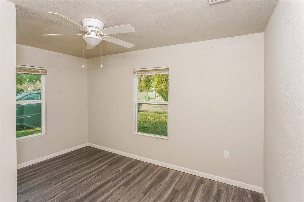 2402 Summer Avenue, Waco, TX 76708 Room featuring wood-finish flooring, two windows with blinds, a white ceiling fan with integrated lighting, and neutral-toned walls