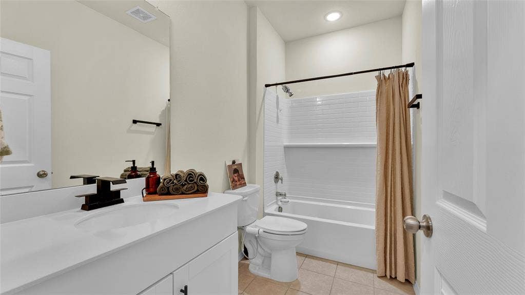 707 Indigo Road, Princeton, TX 75407 Bathroom featuring a white vanity with integrated sink, a rectangular mirror, a shower-over-tub combination with white subway tile surround, and neutral tile flooring