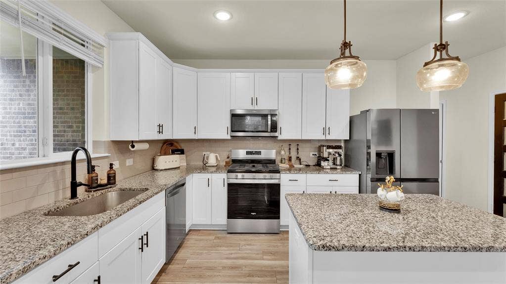 707 Indigo Road, Princeton, TX 75407 Contemporary kitchen featuring white cabinetry, stainless steel appliances, granite countertops, and wood-finish flooring