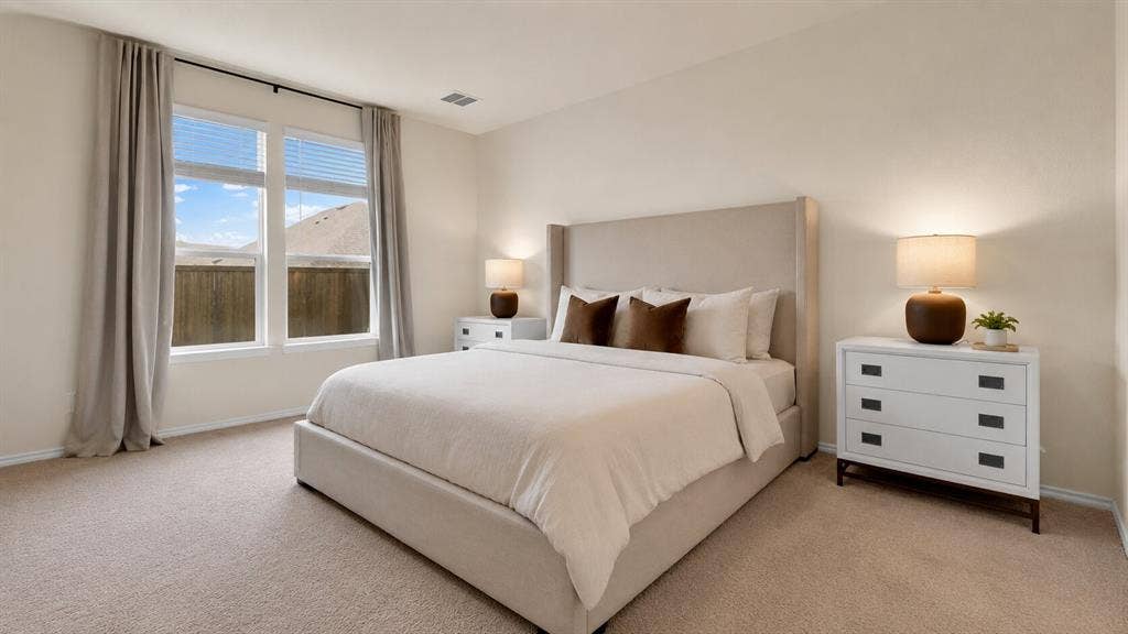 707 Indigo Road, Princeton, TX 75407 Spacious bedroom featuring light-colored carpet, large windows with blinds and drapery rods, and neutral wall tones