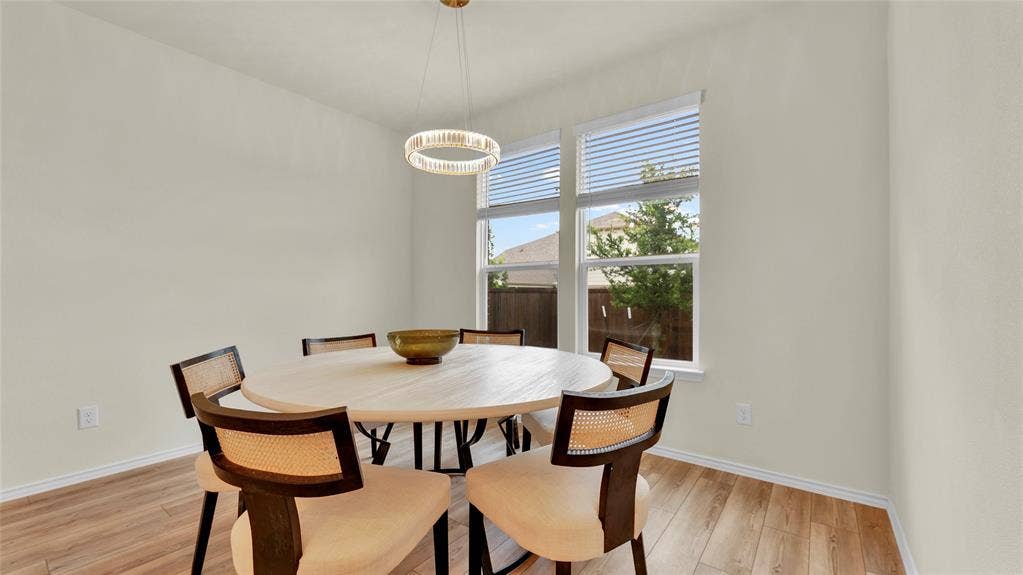 707 Indigo Road, Princeton, TX 75407 Dining area featuring light wood-finish flooring, neutral wall tones, and a modern circular chandelier