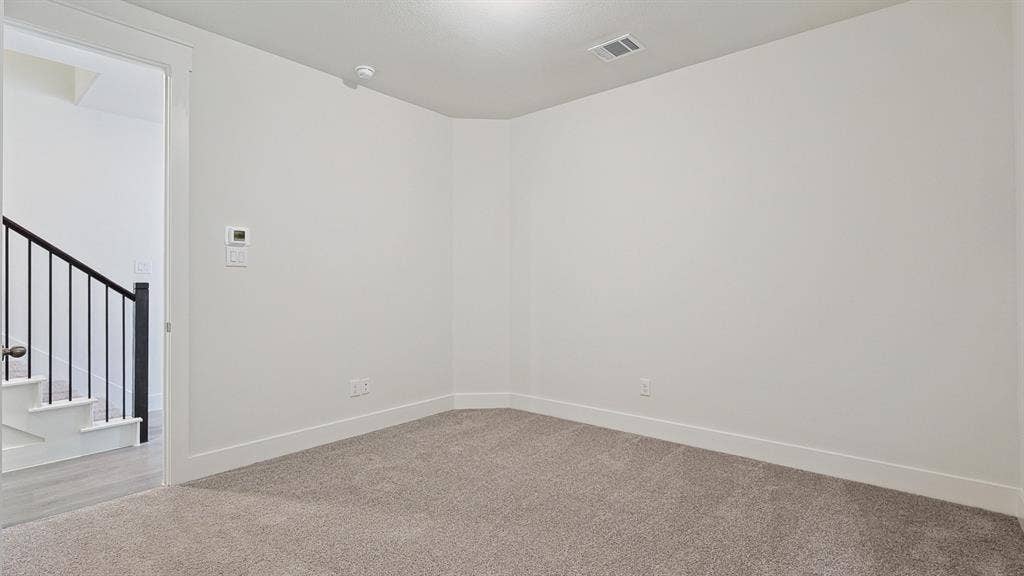 Carpeted room with white walls, white baseboards, and a white ceiling with a single ceiling light fixture