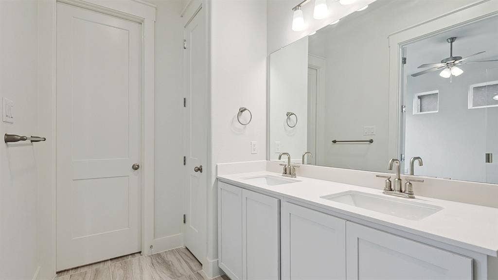 Double vanity with white cabinetry, light-toned countertops, and brushed nickel fixtures