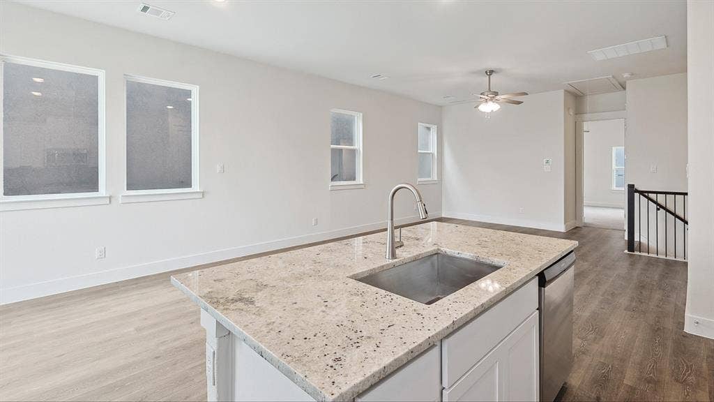 Kitchen island featuring a stainless steel sink, gooseneck faucet, and light-toned granite countertop