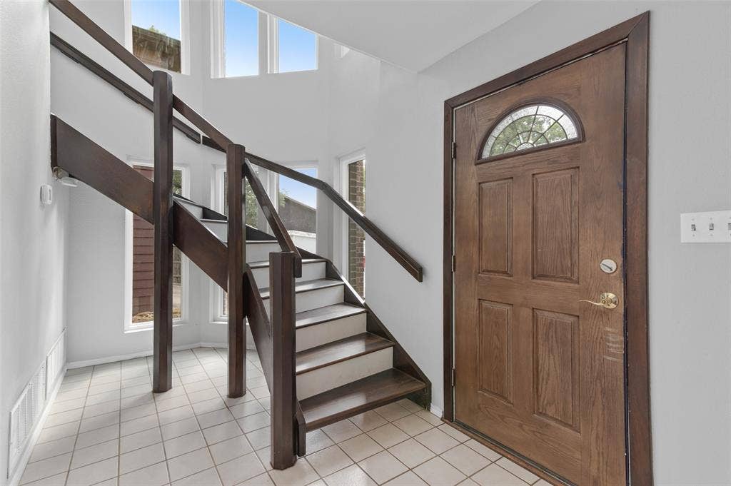 The entry features a dramatic stair case with floor to ceiling windows for lots of natural light.