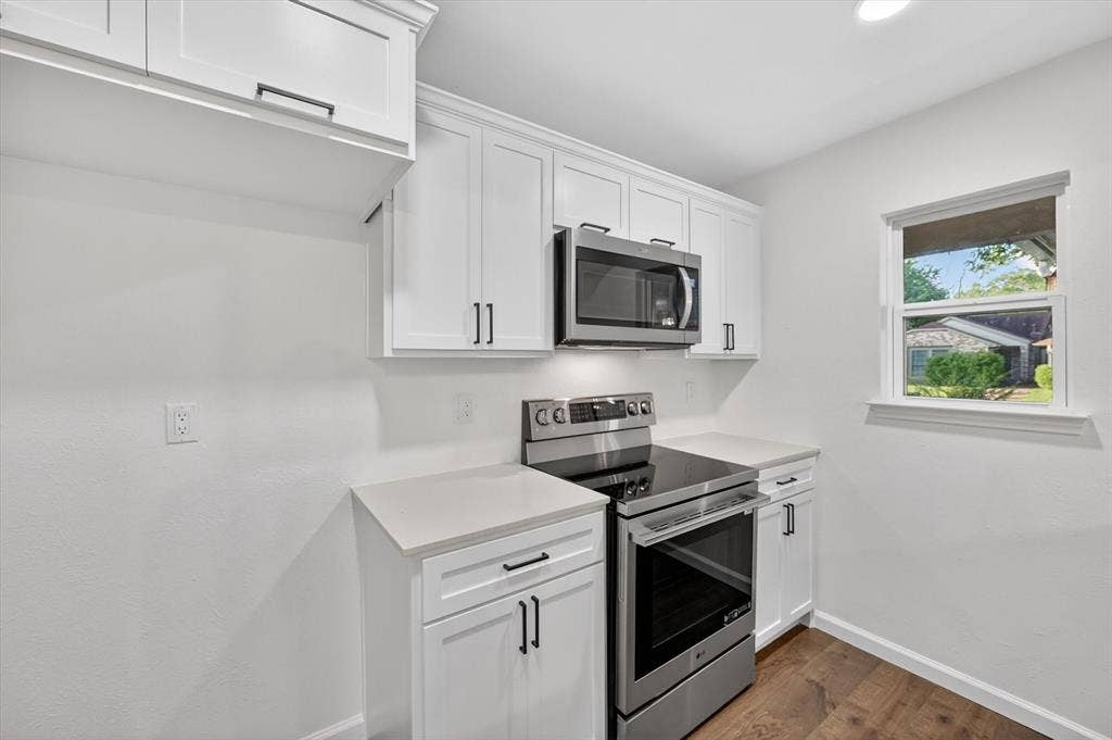 428 Dollins Street, Cedar Hill, TX 75104 Modern kitchen featuring white shaker cabinetry, stainless steel appliances, light countertops, and wood-finish flooring