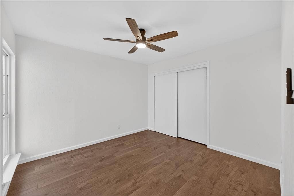 428 Dollins Street, Cedar Hill, TX 75104 Bright interior space featuring wood-finish flooring, a contemporary ceiling fan with integrated lighting, a multi-pane window, white baseboards, and a sliding door closet with white panels