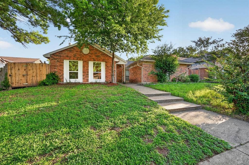 428 Dollins Street, Cedar Hill, TX 75104 Brick facade residence featuring a front lawn, mature trees, and a concrete pathway with steps