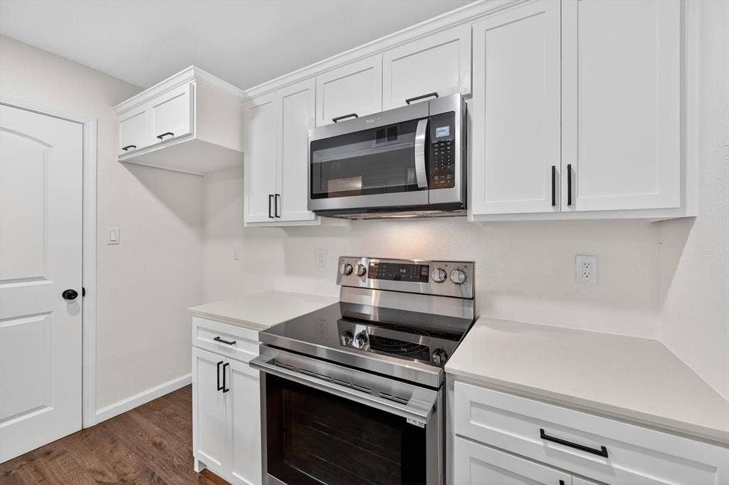 428 Dollins Street, Cedar Hill, TX 75104 Kitchen featuring white shaker cabinetry, stainless steel appliances, light-toned countertops, wood-finish flooring, and a paneled interior door