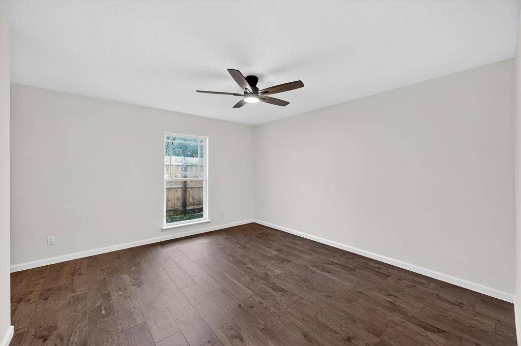 428 Dollins Street, Cedar Hill, TX 75104 Spacious room featuring wood-finish flooring, a contemporary ceiling fan with integrated lighting, a single window with white trim, and light-colored walls
