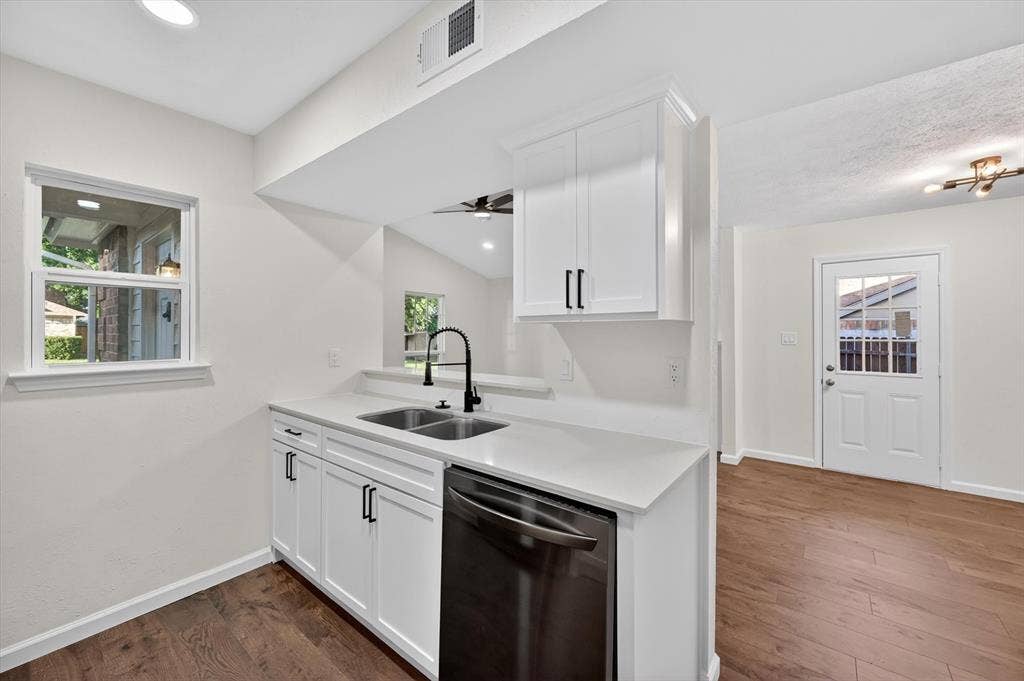 428 Dollins Street, Cedar Hill, TX 75104 Kitchen featuring white cabinetry, light-toned countertops, a dual basin sink with a black gooseneck faucet, and wood-finish flooring