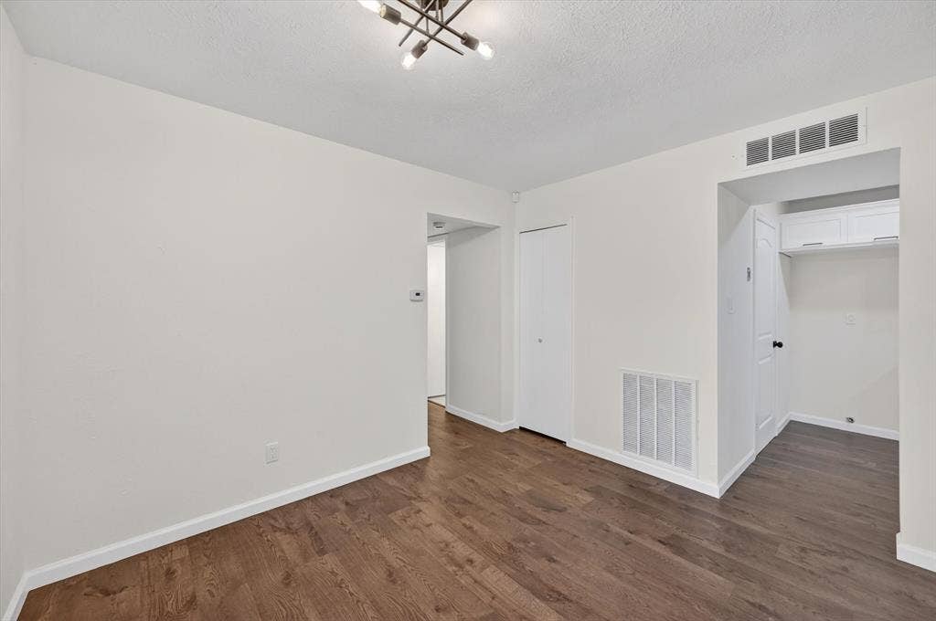 428 Dollins Street, Cedar Hill, TX 75104 Living area featuring wood-finish flooring, white baseboards, a modern ceiling light fixture, and a built-in utility space with upper cabinetry and a tall storage unit