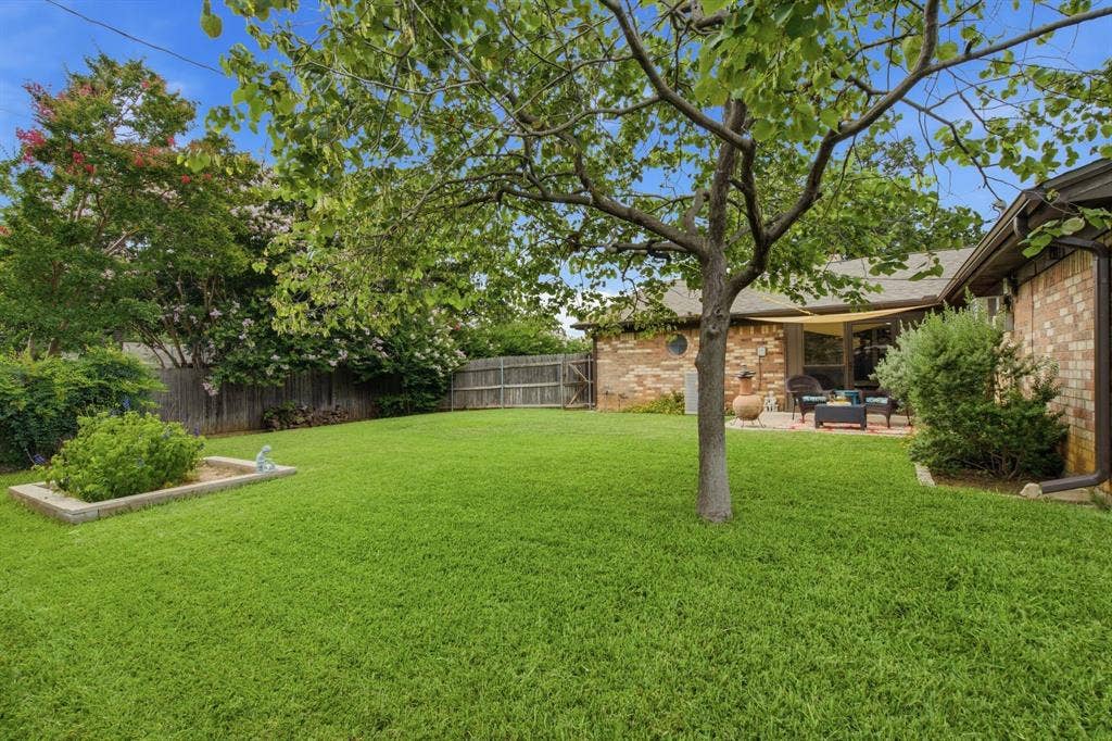 521 W Louella Drive, Hurst, TX 76054 Backyard has lush green grass and lined with crepe myrtles and fenced all around.