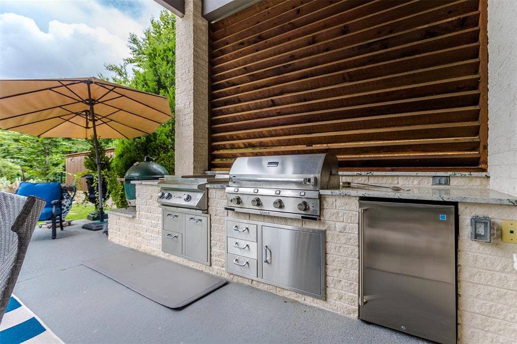 8138 Edgefield Court, Frisco, TX 75035 Outdoor kitchen featuring integrated stainless steel appliances, a built-in refrigerator, and stone veneer cabinetry
