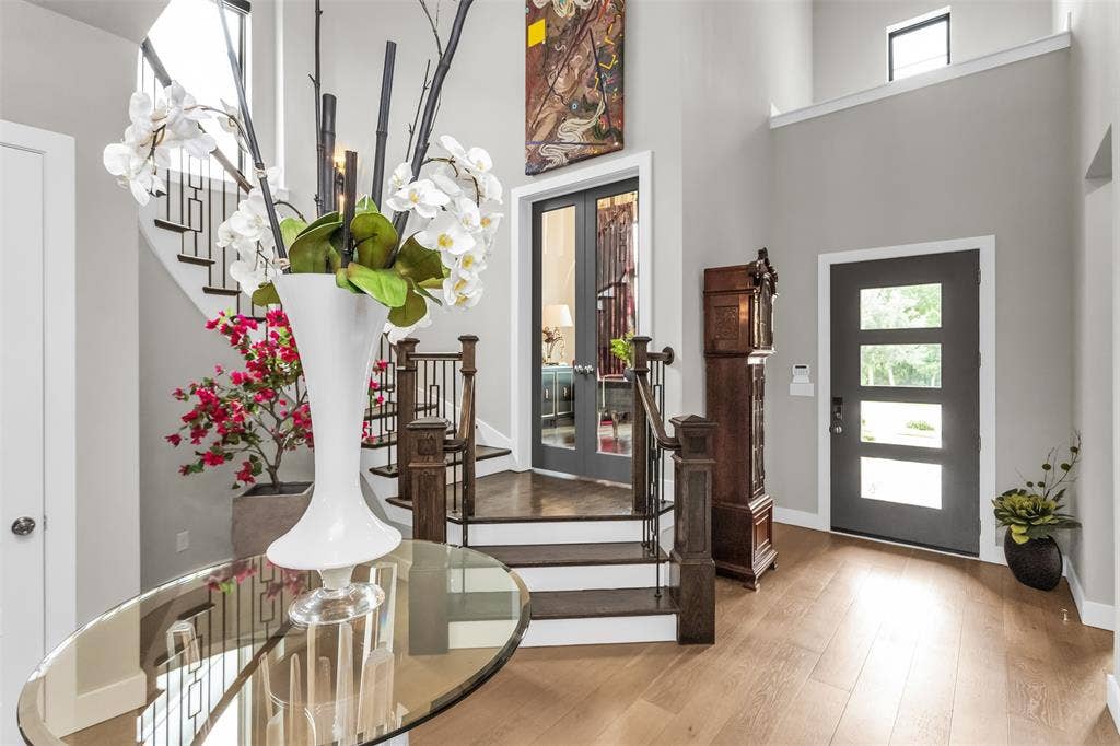 8138 Edgefield Court, Frisco, TX 75035 Grand foyer with high ceilings, light wood-finish flooring, a contemporary staircase featuring dark wood treads and wrought iron railings, and a multi-paneled entry door