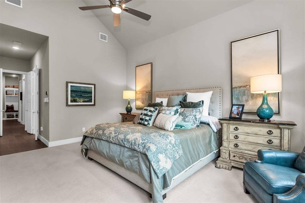 8138 Edgefield Court, Frisco, TX 75035 Vaulted ceiling bedroom featuring plush carpet flooring, a ceiling fan with integrated lighting, and a doorway to a walk-in closet with built-in shelving