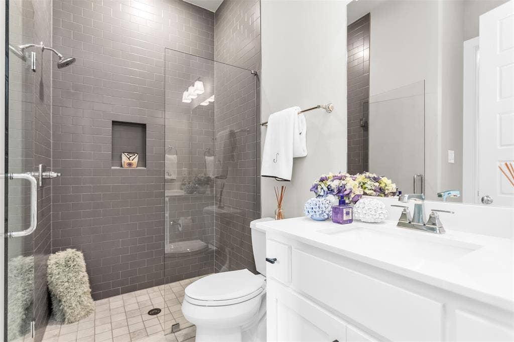 8138 Edgefield Court, Frisco, TX 75035 Bathroom featuring a glass-enclosed shower with gray subway tile walls and an integrated shower niche