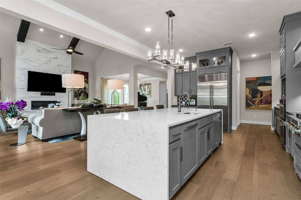 8138 Edgefield Court, Frisco, TX 75035 Gourmet kitchen with a large central island, light-toned wood-finish flooring, and integrated stainless steel appliances
