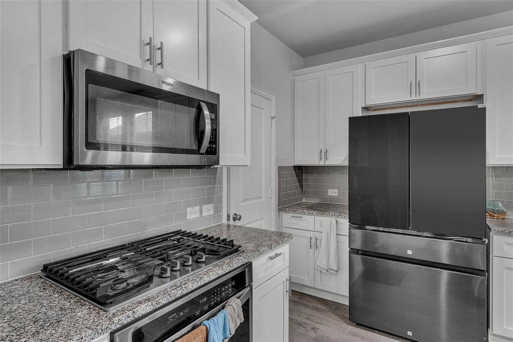 3708 Jan Camille Court, Celina, TX 75009 Kitchen featuring backsplash, light hardwood / wood-style floors, stainless steel appliances, light stone counters, and white cabinets