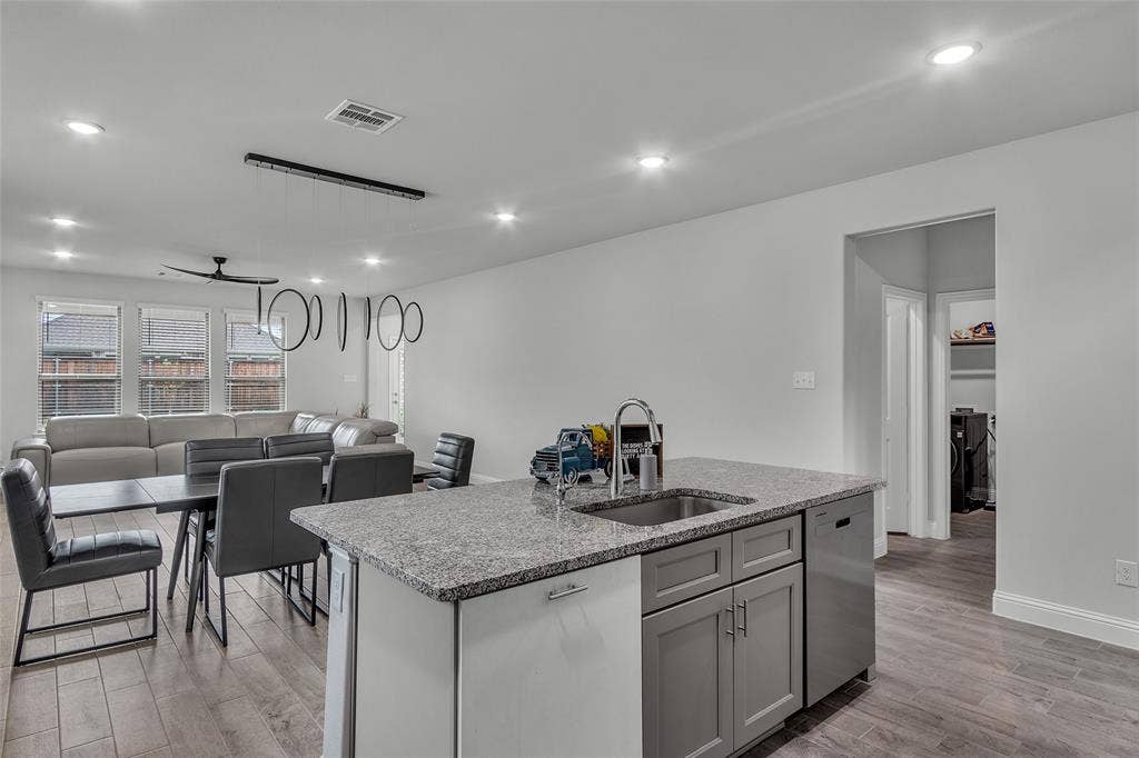 3708 Jan Camille Court, Celina, TX 75009 Kitchen featuring light hardwood / wood-style flooring, an island with sink, stainless steel dishwasher, sink, and light stone counters