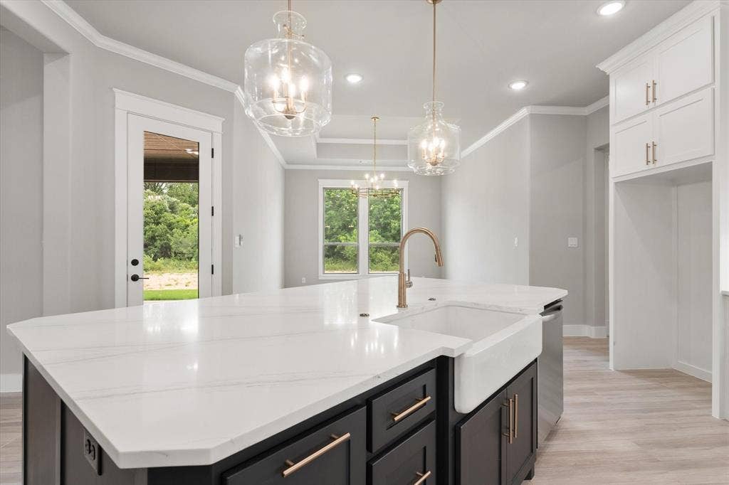 6610 Waggoner Way, Midlothian, TX 76065 Kitchen island featuring a white apron-front sink, a gold-finish faucet, and a light-toned countertop
