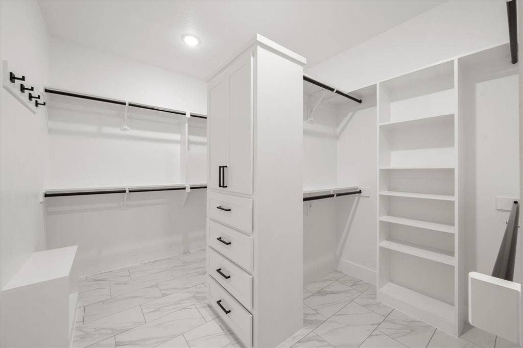 6610 Waggoner Way, Midlothian, TX 76065 Custom closet system featuring white cabinetry, multiple hanging rods, built-in shelving, and drawer storage
