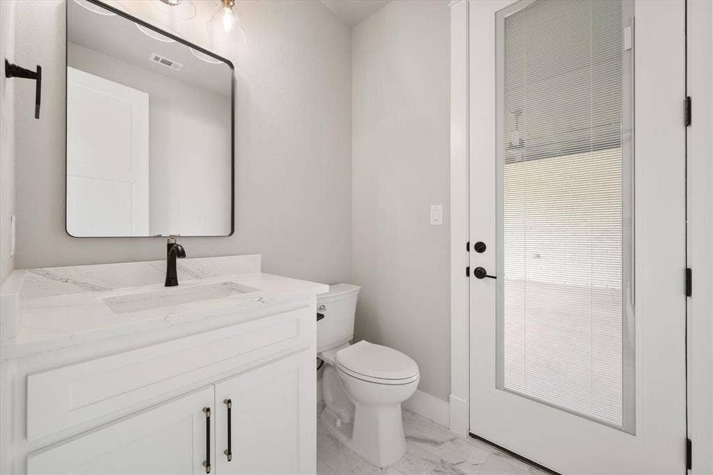 6610 Waggoner Way, Midlothian, TX 76065 Bathroom featuring a white vanity with a rectangular sink, a black faucet, and a framed mirror
