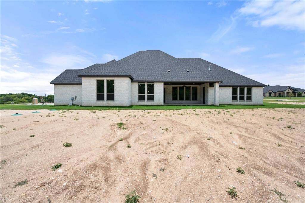 6610 Waggoner Way, Midlothian, TX 76065 Rear exterior showcasing a white brick facade and a dark shingle roof