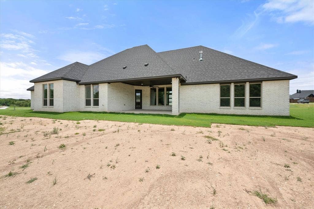 6610 Waggoner Way, Midlothian, TX 76065 Single-story residence featuring light-colored brick exterior, dark asphalt shingle roof, and multiple large windows with dark trim