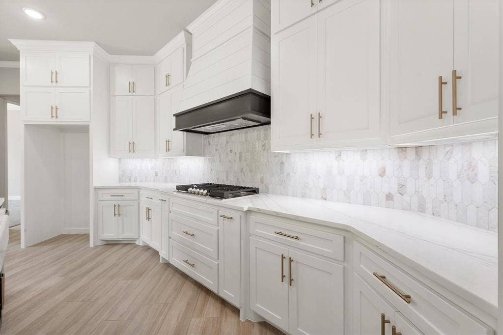 6610 Waggoner Way, Midlothian, TX 76065 Modern kitchen featuring white cabinetry with gold-finish hardware, a gas cooktop, and a white pick-tile backsplash