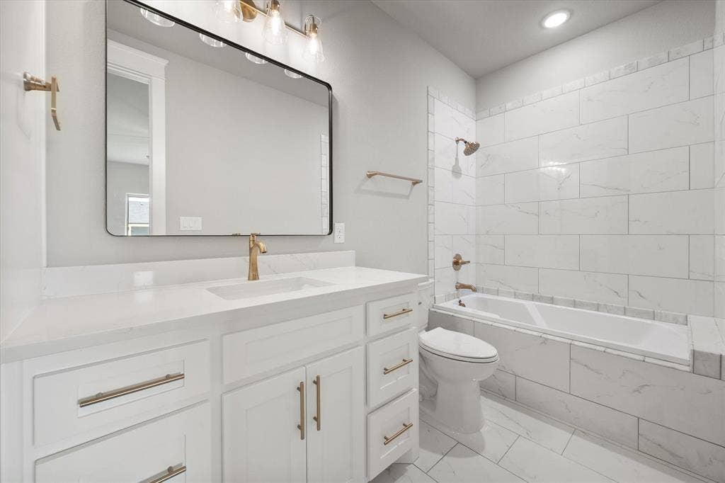 6610 Waggoner Way, Midlothian, TX 76065 Modern bathroom featuring a white vanity with gold-finish hardware, a rectangular undermount sink, and a large black-framed mirror