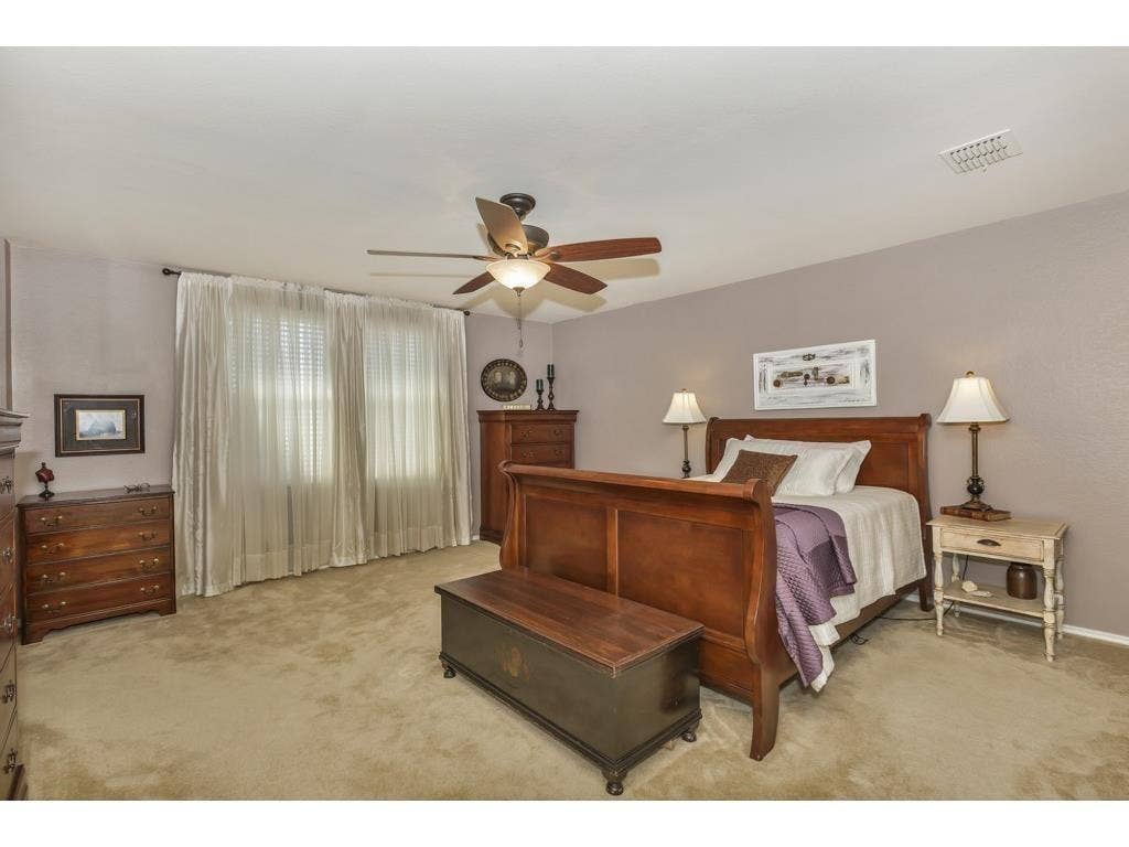 2912 Lake Terrace Drive, Wylie, TX 75098 Spacious room featuring neutral carpeting, a ceiling fan with integrated lighting, and expansive windows dressed with privacy blinds and sheer curtains