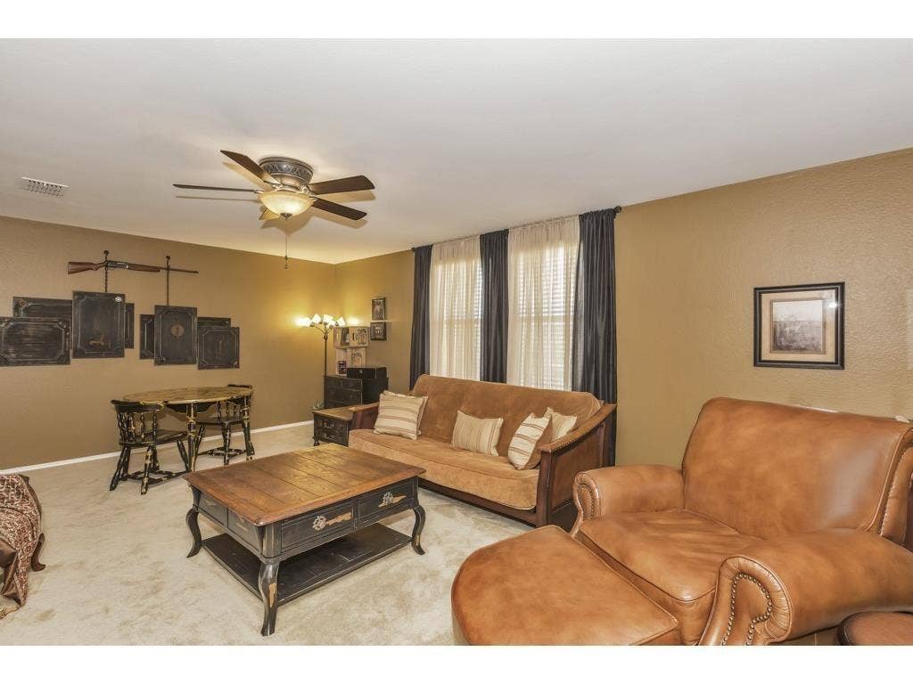 2912 Lake Terrace Drive, Wylie, TX 75098 Carpeted living area featuring a ceiling fan with integrated lighting, textured walls, and windows with blinds and drapery