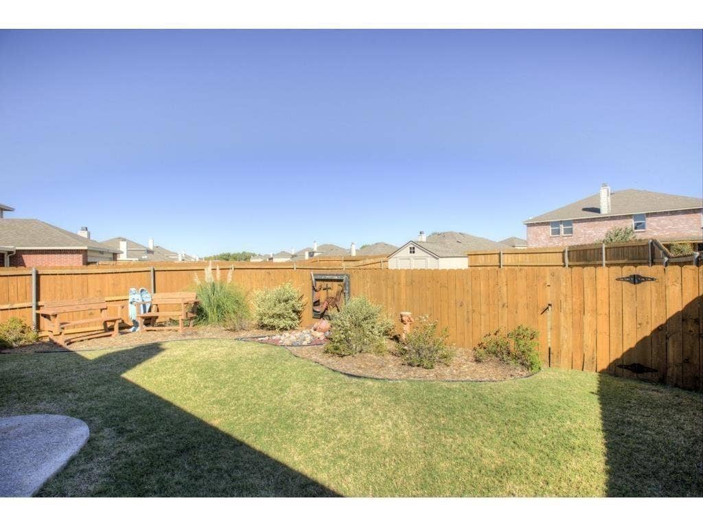 2912 Lake Terrace Drive, Wylie, TX 75098 Spacious backyard featuring a wooden privacy fence, a manicured lawn, and a landscaped garden bed