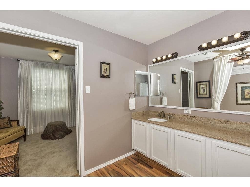 2912 Lake Terrace Drive, Wylie, TX 75098 Vanity area featuring a stone countertop, white cabinetry, integrated sink, and wood-finish flooring