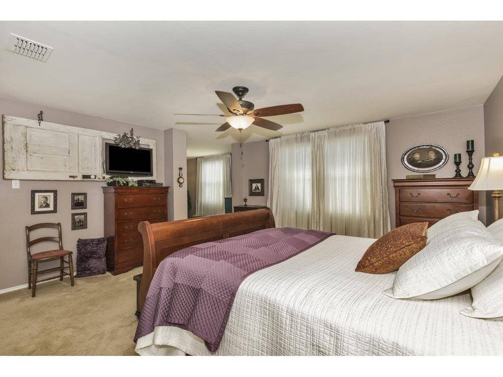 2912 Lake Terrace Drive, Wylie, TX 75098 Carpeted bedroom featuring a ceiling fan with integrated lighting, window with sheer curtains, and a built-in wall niche
