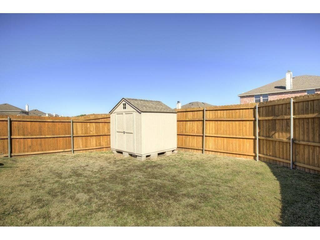 2912 Lake Terrace Drive, Wylie, TX 75098 Fenced backyard featuring a storage shed with a shingle roof