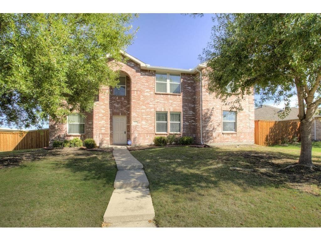 2912 Lake Terrace Drive, Wylie, TX 75098 Two-story brick exterior featuring an arched entryway, multiple windows, a concrete walkway, and a manicured lawn