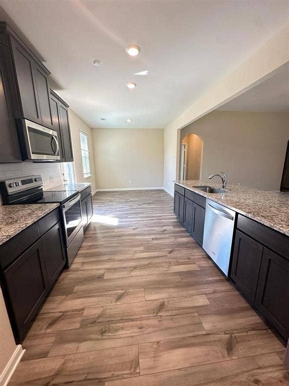 1707 Cotton Blossom Lane, Princeton, TX 75407 Kitchen featuring dark wood cabinetry, granite-style countertops, stainless steel appliances, and wood-finish flooring