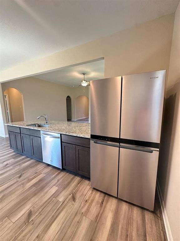 1707 Cotton Blossom Lane, Princeton, TX 75407 Stainless steel refrigerator and dishwasher with a large island featuring dark cabinetry and a speckled countertop