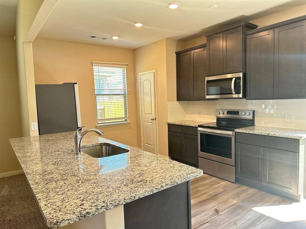 1707 Cotton Blossom Lane, Princeton, TX 75407 Kitchen island with a stainless steel undermount sink and chrome faucet