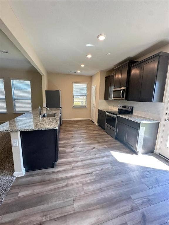 1707 Cotton Blossom Lane, Princeton, TX 75407 Modern kitchen featuring wood-finish flooring, dark cabinetry, and light-toned countertops