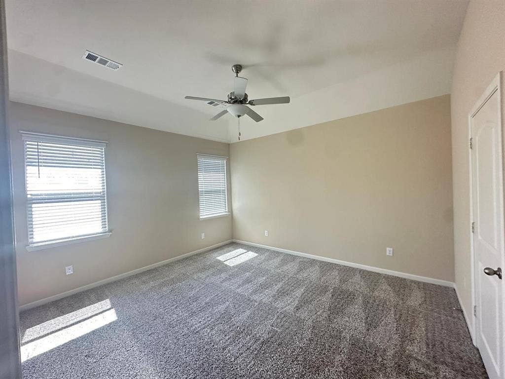 1707 Cotton Blossom Lane, Princeton, TX 75407 Spacious room featuring vaulted ceilings, two windows with blinds, neutral-toned walls, and patterned carpeting